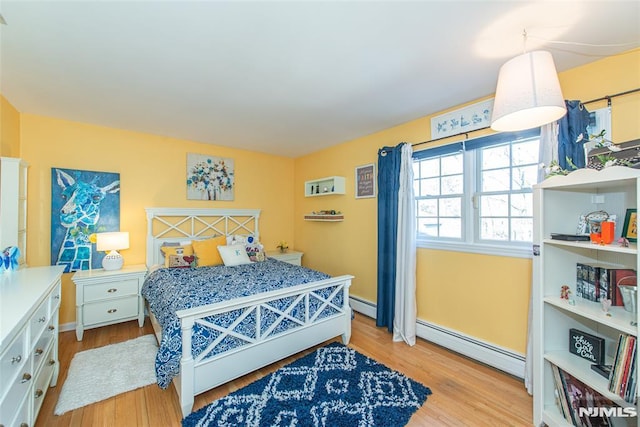 bedroom featuring light wood finished floors and a baseboard radiator