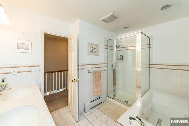 bathroom with visible vents, a wainscoted wall, a sink, a shower stall, and baseboard heating