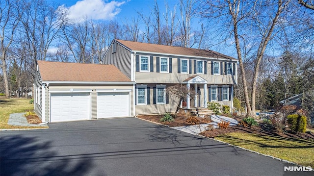 colonial home featuring aphalt driveway, a shingled roof, and a garage