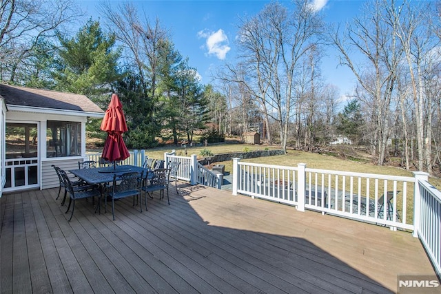 wooden deck with outdoor dining area and a yard