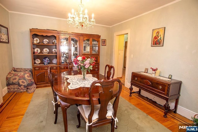 dining room with baseboards, a chandelier, ornamental molding, and light wood finished floors