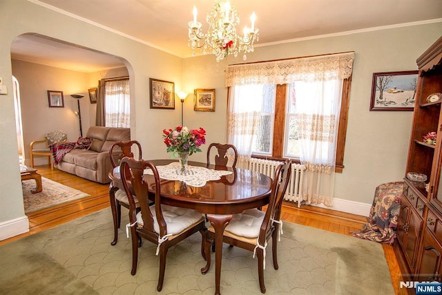 dining room with crown molding, radiator, a healthy amount of sunlight, and arched walkways