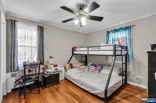 bedroom with ornamental molding, a ceiling fan, baseboards, and hardwood / wood-style flooring