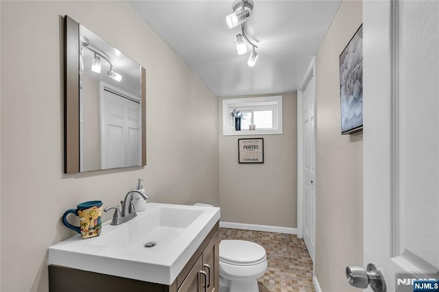 bathroom featuring toilet, vanity, and baseboards