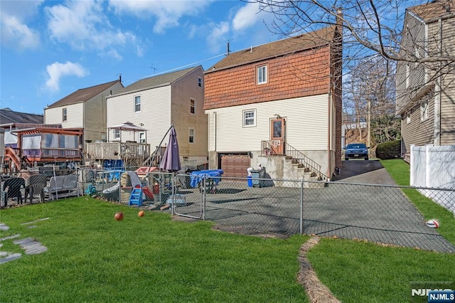 rear view of house featuring a yard, entry steps, driveway, and fence