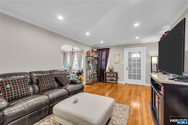 living area featuring arched walkways, crown molding, and light wood-style floors