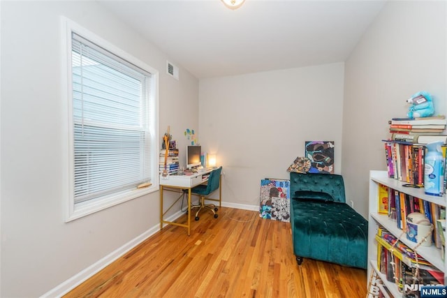 living area featuring visible vents, baseboards, and wood finished floors