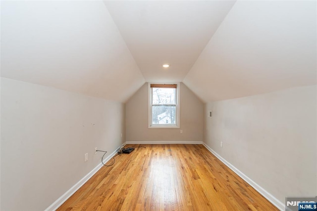 bonus room with lofted ceiling, baseboards, and light wood-type flooring