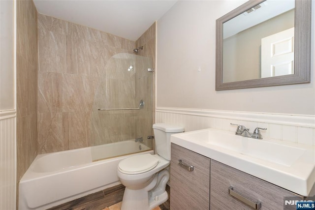 full bath with wood finished floors, visible vents, a wainscoted wall, bathtub / shower combination, and toilet