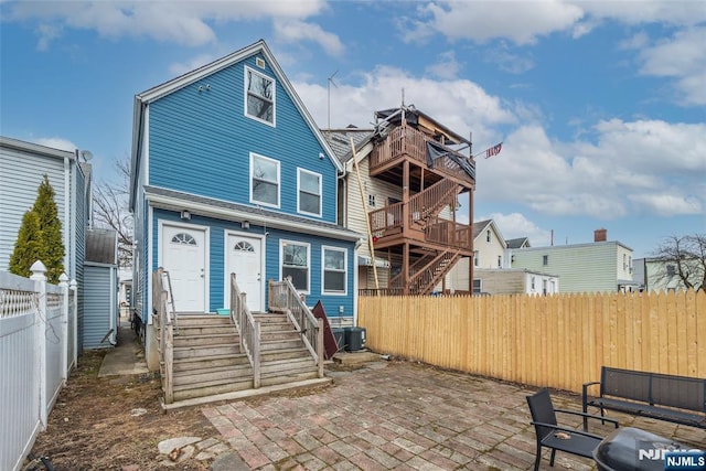 view of front of home featuring central air condition unit, a patio, and a fenced backyard