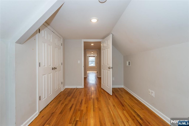 additional living space with vaulted ceiling, light wood-style floors, and baseboards