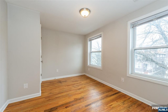 unfurnished room with baseboards and light wood finished floors