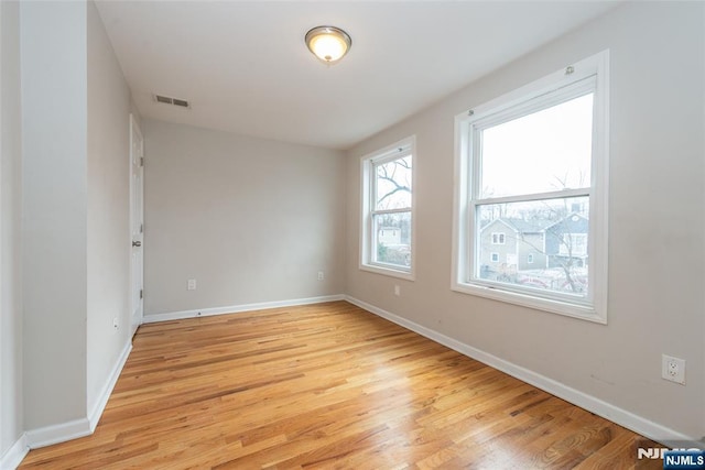 spare room featuring baseboards, visible vents, and light wood finished floors