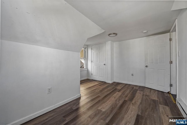 bonus room with a baseboard heating unit, wood finished floors, and baseboards