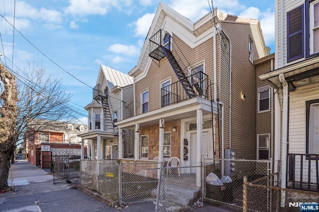 view of front of home with a fenced front yard, metal roof, a balcony, and a gate