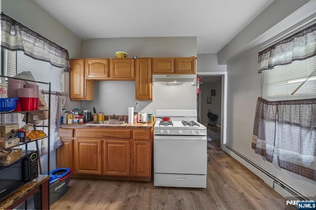 kitchen featuring a baseboard heating unit, under cabinet range hood, white gas range oven, wood finished floors, and a sink