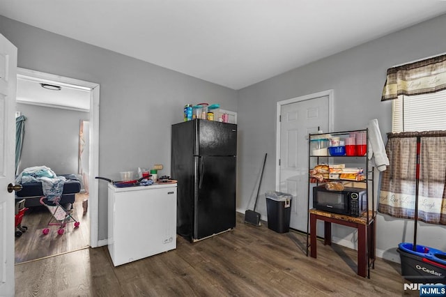 kitchen with baseboards, dark wood-type flooring, and black appliances