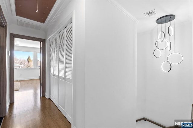 hall featuring visible vents, wood finished floors, attic access, and ornamental molding