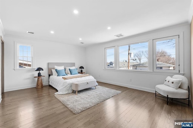 bedroom featuring visible vents, multiple windows, and wood finished floors