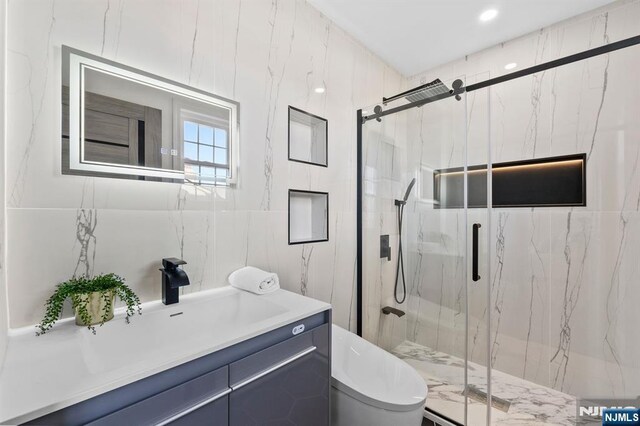 full bath featuring a marble finish shower, vanity, toilet, and tile walls