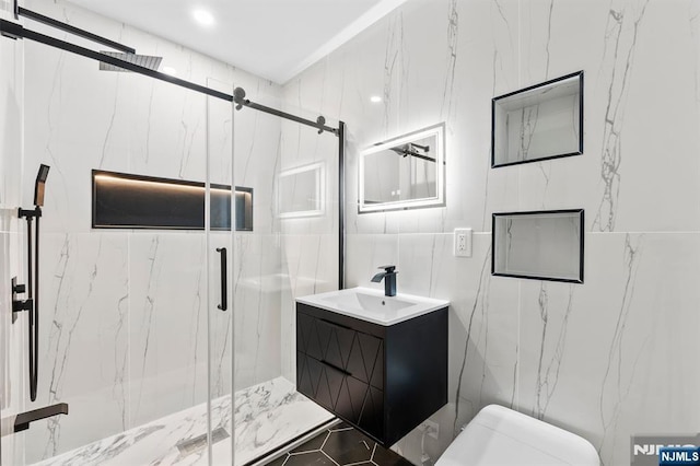 full bath featuring vanity, tile walls, toilet, and a marble finish shower