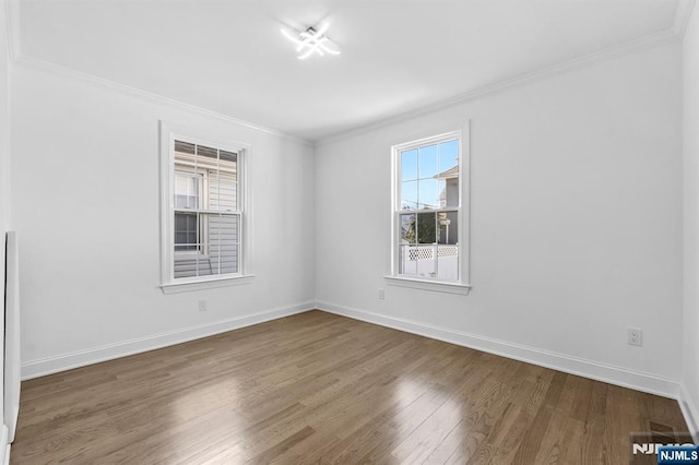 empty room featuring crown molding, wood finished floors, and baseboards