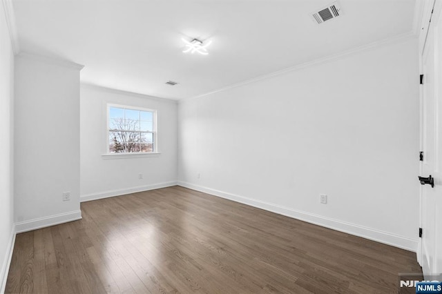 empty room featuring dark wood finished floors, crown molding, visible vents, and baseboards