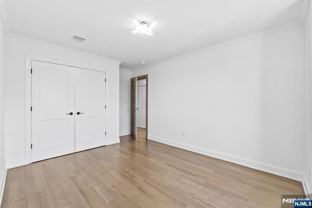 unfurnished bedroom featuring visible vents, light wood-style flooring, a closet, crown molding, and baseboards