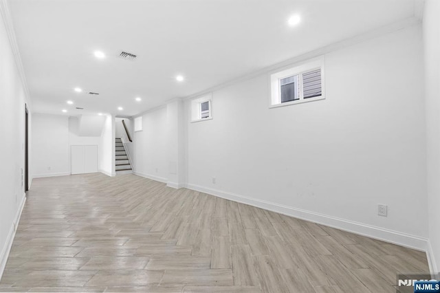 finished below grade area featuring baseboards, stairs, and crown molding