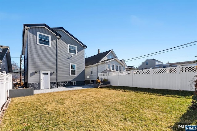 rear view of property featuring a patio, a lawn, and a fenced backyard