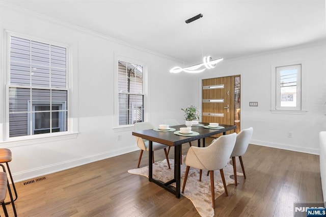 dining area with visible vents, baseboards, dark wood finished floors, and crown molding