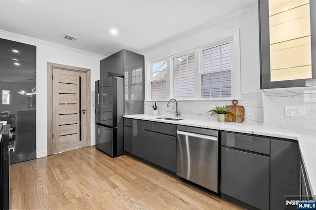 kitchen featuring visible vents, gray cabinets, a sink, stainless steel dishwasher, and freestanding refrigerator