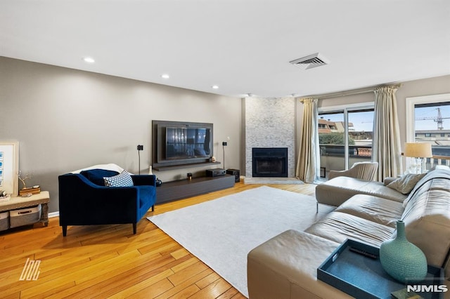 living room featuring visible vents, recessed lighting, light wood-style floors, a fireplace, and baseboards