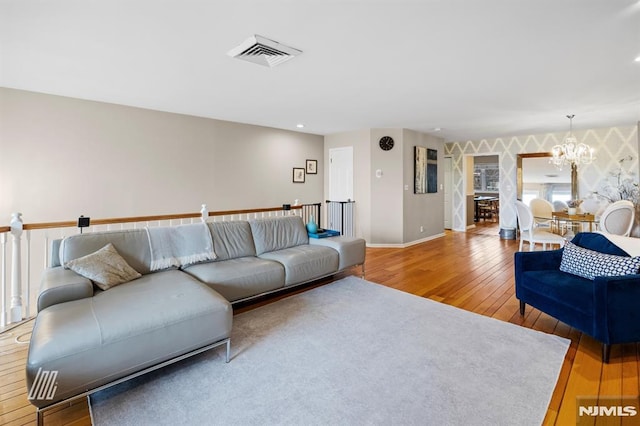 living room featuring visible vents, baseboards, a notable chandelier, and hardwood / wood-style flooring