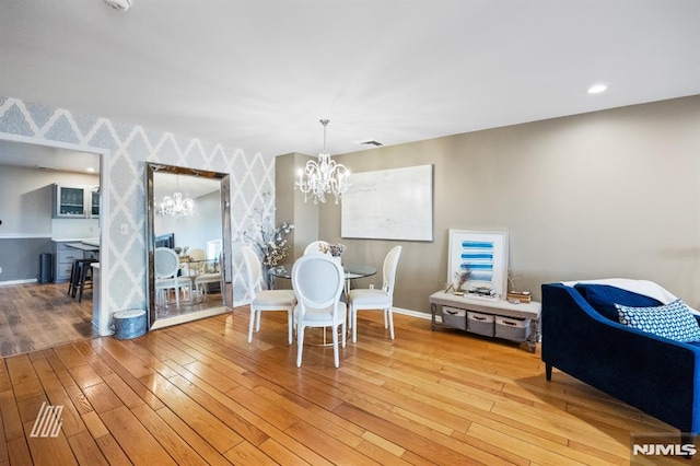 dining area with visible vents, light wood finished floors, a notable chandelier, wallpapered walls, and baseboards