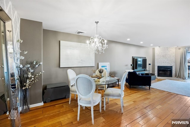 dining room featuring a fireplace, light wood-style floors, visible vents, and baseboards