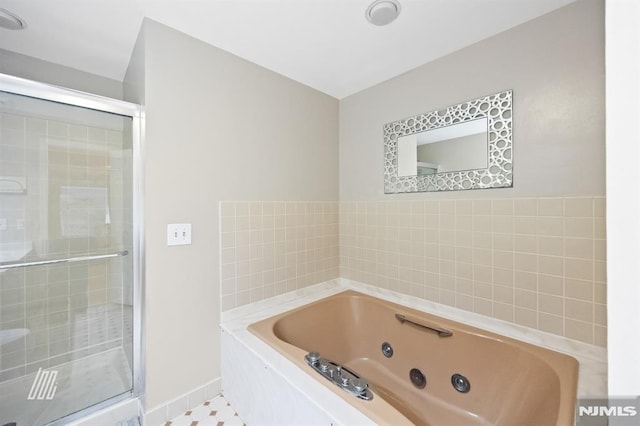 bathroom with a shower stall, a jetted tub, and baseboards