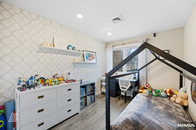 bedroom with visible vents, wallpapered walls, an accent wall, recessed lighting, and light wood-style floors