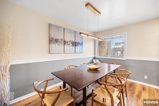 dining area with baseboards and wood finished floors