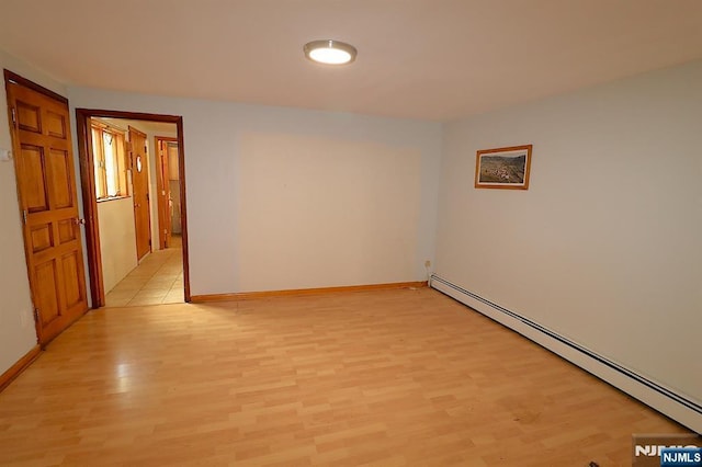 spare room with light wood-type flooring, a baseboard radiator, and baseboards