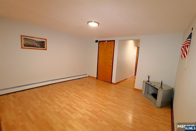 empty room with baseboards, baseboard heating, and light wood finished floors