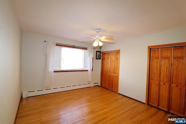 unfurnished bedroom with baseboard heating, two closets, light wood-type flooring, and ceiling fan