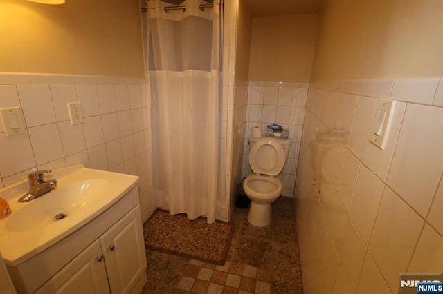 bathroom with a shower with shower curtain, vanity, toilet, and tile walls