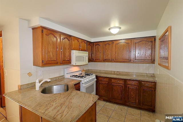 kitchen with light tile patterned floors, brown cabinets, white appliances, and a sink