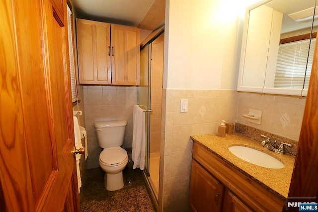 full bath with vanity, tile walls, toilet, and a shower stall