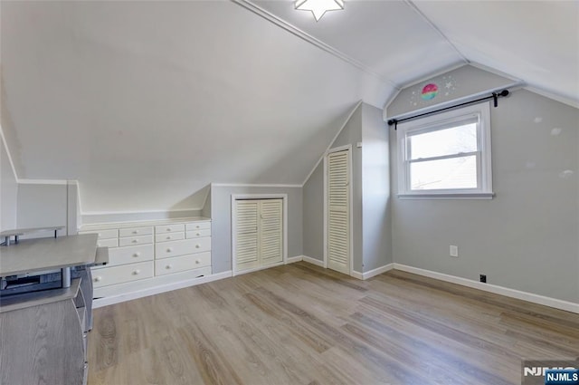 additional living space featuring vaulted ceiling, light wood-style floors, and baseboards