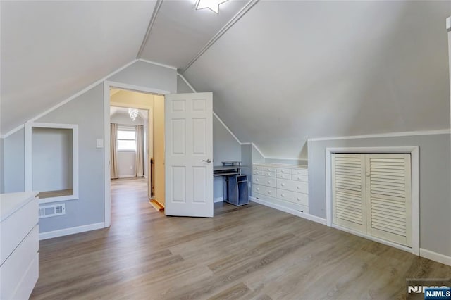 additional living space featuring visible vents, lofted ceiling, baseboards, and wood finished floors