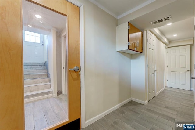 hallway with visible vents, baseboards, ornamental molding, and wood tiled floor