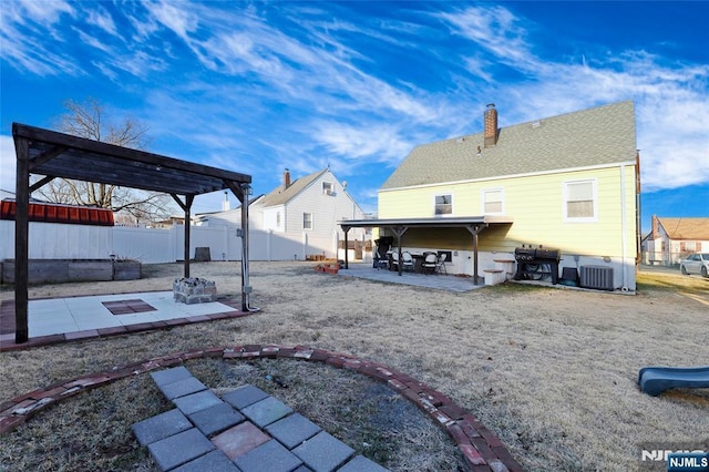 back of property featuring fence, a shingled roof, a chimney, central air condition unit, and a patio area