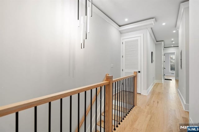 hall with an upstairs landing, recessed lighting, light wood-style floors, crown molding, and baseboards